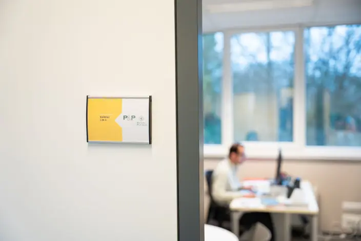 Numéro de bureau avec en arrière plan un membre travaillant dans son bureau privé