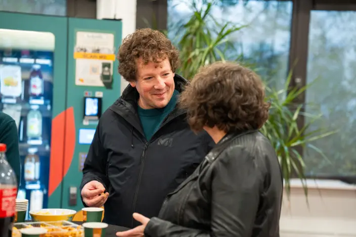 Femme et homme discutant ensemble lors d'un networking professionnel autour de snacks et de boissons
